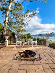 un patio con mesa, sillas y chimenea en The Seaside Cottage A little gem by the sea, en Tinderbox