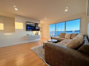 a living room with a couch and a large window at Seaside Chic Villa with Breathtaking Ocean Views in Howrah