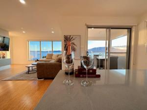two wine glasses sitting on a table in a living room at Seaside Chic Villa with Breathtaking Ocean Views in Howrah