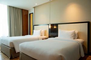 two beds in a hotel room with white sheets at DoubleTree by Hilton-Pune Chinchwad in Pune