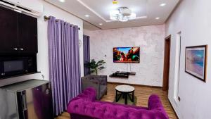 sala de estar con sofá púrpura y TV en James Court Hotel & Luxury Apartments, en Lekki