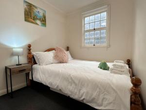 a bedroom with a bed with white sheets and a window at Hobart City Oasis with 3 beds in Hobart