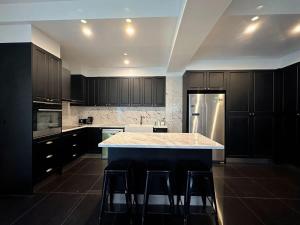 a kitchen with black cabinets and a kitchen island with bar stools at City Retreat for 8 with Spacious Rooms in Hobart