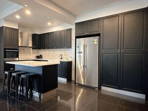 a kitchen with black cabinets and a stainless steel refrigerator at City Retreat for 8 with Spacious Rooms in Hobart +22 photos