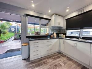 a kitchen with white cabinets and a large window at Fonton Blue Holiday Home close to City and Airport in Moonah