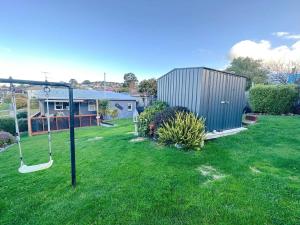a swing in a yard with a house at Fonton Blue Holiday Home close to City and Airport in Moonah