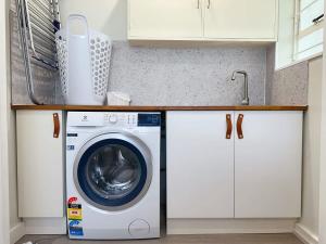 a washing machine in a kitchen with white cabinets at SandyBay Garden Hideaway in Sandy Bay