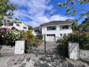 a white house with a gate and flowers at SandyBay Garden Hideaway in Sandy Bay