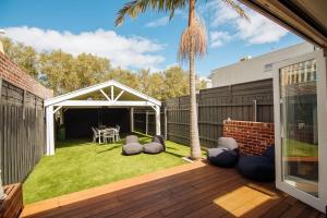 a backyard with a deck with a palm tree at SENSATIONAL Renovated Cottage in Beautiful Seddon in Seddon