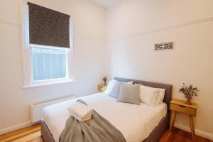 una camera da letto con un grande letto bianco con una finestra di SENSATIONAL Renovated Cottage in Beautiful Seddon a Seddon
