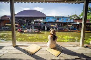 uma mulher sentada numa doca a olhar para um rio em LOYD Ratchaburi em Ban Tha Nat (4)
