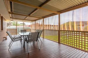 a screened in porch with a table and chairs at Cozy Family Friendly Werribee Home in Werribee