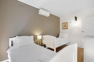 a white bedroom with a white bed and a chair at The Starfish Cottage - 250m to bay beach in Rye