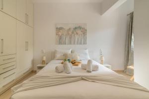 ein weißes Schlafzimmer mit einem großen weißen Bett mit Kissen in der Unterkunft Citrea Stylish House with Garden near Beach in Heraklion