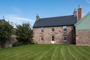 a large brick house with a large grass yard at Dryburgh Farmhouse in Saint Boswells