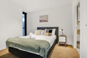 a bedroom with a large white bed with a night stand at Central 15th floor Apt near Flagstaff & QV Market in Melbourne