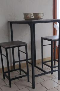 a black table and two stools on a floor at Chambre lit double, Salon, cuisine, jardin in Couze-et-Saint-Front +1 photo