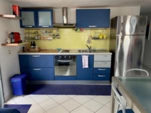 cocina con armarios azules y nevera de acero inoxidable en L14 Bilocale in residence con piscina, en Porto Recanati