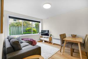 een woonkamer met een bank en een raam bij Homey 1 bdrm Thornbury Apt near restaurants+shops in Melbourne