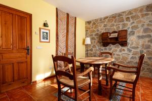 Habitación con mesa, sillas y pared de piedra. en Casa Angel Caldueño, 