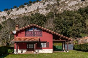 una casa roja frente a una montaña en Casa Angel Caldueño, 