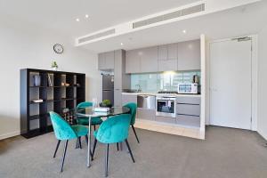 a kitchen with a glass table and blue chairs at Grosvenor on Queens Luxury Melbourne CBD Apt in Melbourne