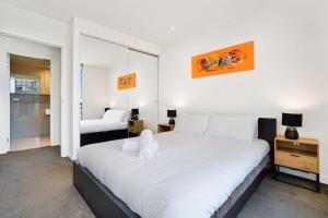 a bedroom with a large white bed in a room at Grosvenor on Queens Luxury Melbourne CBD Apt in Melbourne