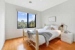 een witte slaapkamer met een bed en een groot raam bij Bundoora Family Home near Uni Hill in Bundoora