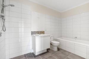een witte badkamer met een toilet en een bad bij Bundoora Family Home near Uni Hill in Bundoora