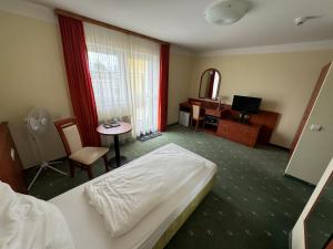 a hotel room with a bed and a table and a television at Hotel Breitenlee in Vienna