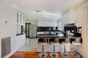 een keuken met zwarte aanrechtbladen en barkrukken bij Prized Home Away from Home in Enviable Location in Narre Warren South