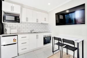 a kitchen with white cabinets and a sink and two chairs at Gem in heart of Melbourne CBD in Melbourne