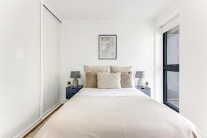 una camera bianca con un grande letto e due finestre di The Wandsworth Luxury Apartment a Londra