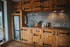 a kitchen with wooden cabinets and a tile wall at Brīvdienu māja Straumēni in Pāle