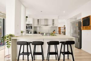 a kitchen with a island with four bar stools at Deluxe Family Montpellier Gardens Estate - Burwood in Burwood +9 photos
