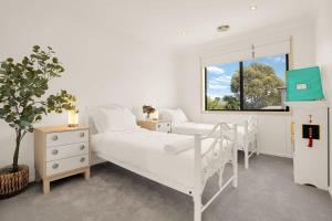 a white bedroom with a bed and a window at Deluxe Family Montpellier Gardens Estate - Burwood in Burwood