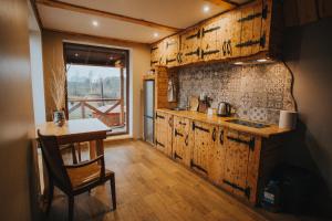 a kitchen with wooden cabinets and a table with a chair at Brīvdienu māja Straumēni in Pāle