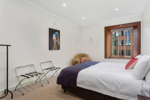 a bedroom with a bed and two chairs and a window at Heritage Building Penthouse CBD Apartment in Hobart