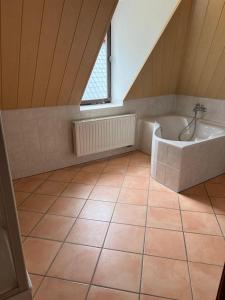 uma casa de banho no sótão com uma banheira e uma janela em Wolke 7 em Freital