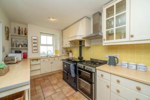 a kitchen with white cabinets and a stove top oven at Rosemary Cottage in Mortehoe