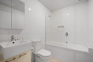 a white bathroom with a toilet and a sink at A River-side 2bdm Footscray Oasis + Parking in Melbourne +9 photos