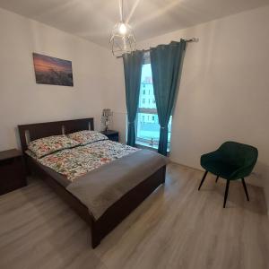 a bedroom with a bed and a chair and a window at Apartament Centre in Giżycko