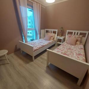 two beds in a room with a window at Apartament Centre in Giżycko