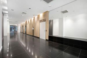 um corredor de um edifício com piso de azulejo preto em Panoramic View CBD 1 Bed Apt +OFFICE (Collins) em Melbourne