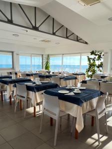 un comedor con mesas azules y sillas blancas en Hotel Ideal en Cupra Marittima