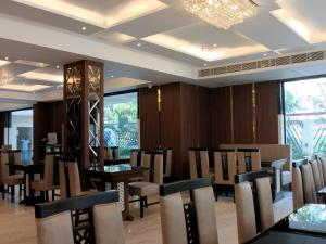een eetkamer met tafels en stoelen en een kroonluchter bij AGM GRAND HOTEL & Spa in Digha