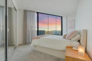 een slaapkamer met een bed en een groot raam bij Stylish Bay-Side Executive Apt w parking in Melbourne