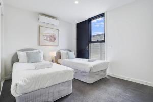 a white room with two beds and a window at Contemporary Central Brunswick 2-Story Townhouse* in Melbourne
