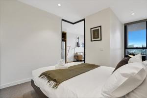 a white bedroom with a large bed and a window at Richmond Heritage Executive Apt for 2 w parking in Melbourne