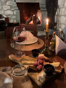 a table with a wine glass and cheese and a fireplace at Bujtina Adora 